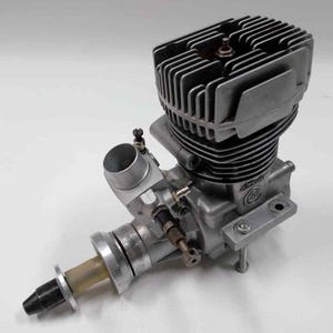 Può includere: Un motore modello color argento con una testata cilindrica alettata e diversi componenti. Il motore ha un corpo cilindrico, un carburatore e un albero dell'elica. È progettato per modellini di aerei o altre applicazioni su piccola scala.