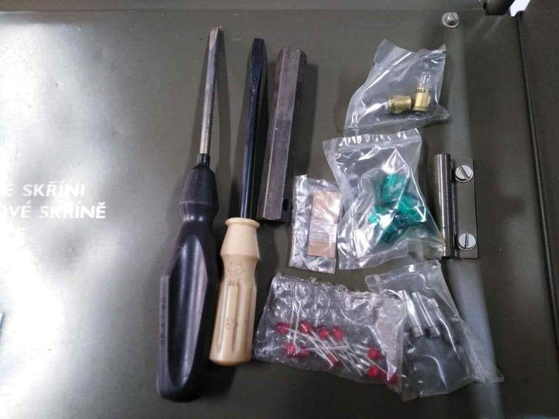 Peut inclure: Ensemble d'outils et de composants mat&eacute;riels, comprenant des tournevis, des barres m&eacute;talliques et de petites pi&egrave;ces dans des sachets en plastique transparent. L'ensemble est dispos&eacute; sur une surface verte.