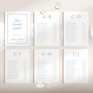 May include: A collection of elegant wedding stationery, including table cards and a welcome sign. The cards feature a minimalist design with pale blue text on a white background. The welcome sign reads "Our favorite people!" and includes the names Olivia & Thomas.
