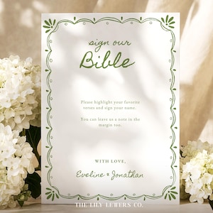 May include: A white rectangular sign with a green hand-drawn border featuring the text: sign our Bible, Please highlight your favorite verses and sign your name. You can leave us a note in the margin too. WITH LOVE, Eveline & Jonathan, THE LILY LETTERS CO.