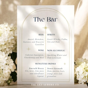May include: A white bar menu sign with navy blue text and gold accents. The sign lists beer, spirits, wine, non-alcoholic drinks, and signature cocktails. The sign is decorated with floral arrangements.