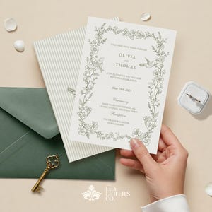 May include: Wedding invitation suite featuring a floral design with the names Olivia and Thomas. Includes a green envelope, striped card, and a small ring box with a ring. A vintage key is also present.