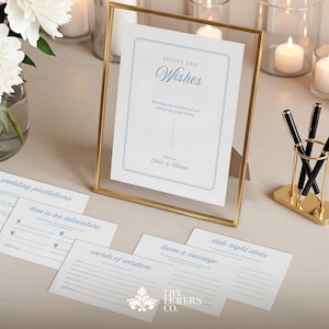 Può includere: Un cartello con cornice dorata con le parole "ADVICE AND Wishes" e diverse carte con suggerimenti per un matrimonio. Un vaso di fiori bianchi e candele sono sullo sfondo. Penne nere sono in un portapenne dorato.