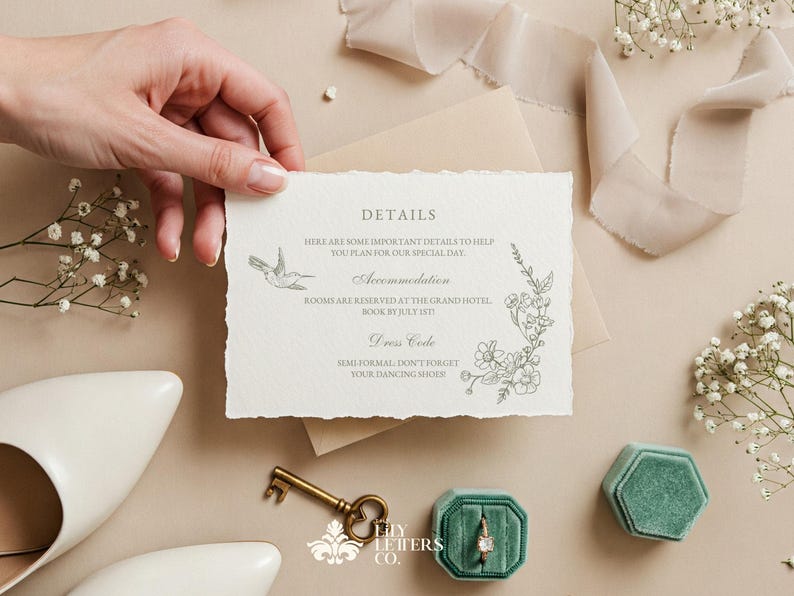 May include: A wedding invitation with torn edges, featuring floral and hummingbird illustrations. The invitation is held by a hand, with a key, ring box, and shoes in the background. The text on the invitation reads "DETAILS".