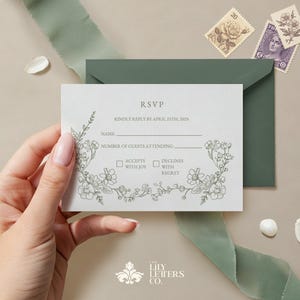 May include: A light gray RSVP card with floral illustrations and the text "RSVP". The card is held near a green envelope and ribbon. Two vintage stamps and decorative elements are also present. The Lily Letters Co. logo is at the bottom.
