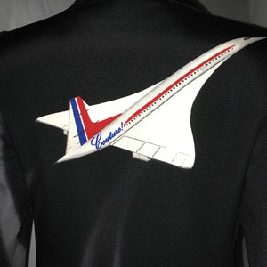 May include: Black blazer with a white and red Concorde airplane patch on the back. The patch includes the word "Couture!" in a cursive font. The blazer is displayed on a mannequin.