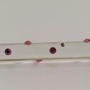 May include: A clear glass rod with a silver metal end piece and a crystal ball on the other end. The rod is decorated with small pink dots.