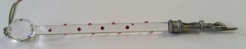 May include: A clear glass rod with a silver metal end piece and a crystal ball on the other end. The rod is decorated with small pink dots.