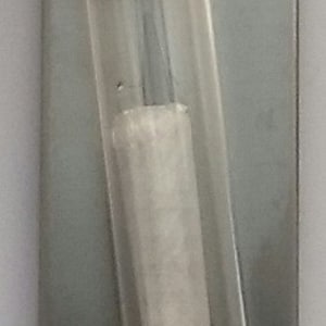 May include: A silver metal plaque with a small, silver, decorative design at the top. A glass tube with a cork stopper contains a rolled up piece of white paper with the Hebrew word "T'V" written on it.