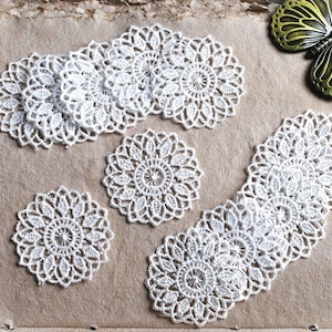 May include: Several white, intricately crocheted doilies in various shapes and sizes are arranged on a textured, light brown surface. The doilies feature a delicate, floral-inspired design. A decorative butterfly is in the upper right corner.