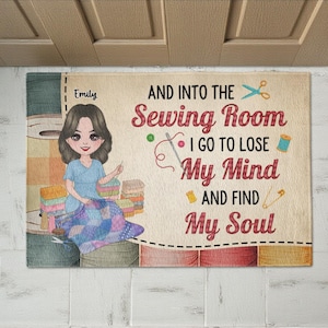 Puede incluir: Una alfombra rectangular con temática de costura. La alfombra presenta una ilustración de dibujos animados de una mujer cosiendo, junto con el texto "AND INTO THE Sewing Room I GO TO LOSE My Mind AND FIND My Soul". La alfombra es beige con acentos coloridos.