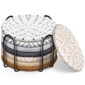 May include: A set of seven round coasters in various neutral colors, including white, gray, and brown, with a woven rope design. The coasters are stacked in a black metal holder, with one coaster leaning against the stack.