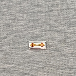Könnte beinhalten: Ein rechteckiges, silberfarbenes modulares Armbandglied mit einem mittigen, goldfarbenen Hängebrücken-Motiv und roten Akzenten. Der Charm besitzt eine polierte metallische Oberfläche und eine flache, längliche Form zum Einsetzen.