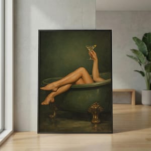 May include: A framed art print depicts a person relaxing in a green clawfoot bathtub, holding a martini with a lemon twist. The artwork has a vintage aesthetic, with a dark green background and gold accents on the tub.