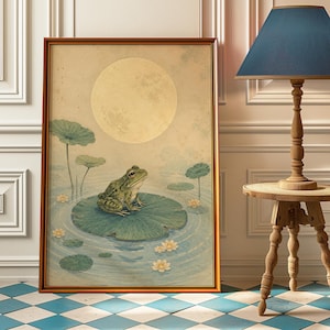 Peut inclure: Impression d'art encadrée représentant une grenouille verte sur une feuille de nénuphar dans un étang, avec une grande lune en arrière-plan. L'œuvre d'art a une esthétique vintage, avec des couleurs douces et une atmosphère sereine. Le cadre est de couleur marron chaud.