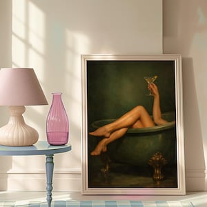 May include: A framed artwork depicts a person relaxing in a green bathtub, holding a cocktail. The artwork is propped against a wall. A pink lamp and vase sit on a blue side table, with a blue and white checkered rug in the foreground.
