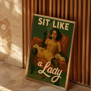 May include: Framed vintage-style print with a green background and the text "SIT LIKE a Lady." The artwork depicts a woman in yellow lingerie, black gloves, and stockings, smoking a cigarette while seated in a red armchair.