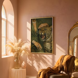 May include: A framed artwork featuring a leopard with a pearl necklace, roaring with its mouth open. The artwork is set against a green background, with a person's arm and hand adorned with jewelry. The frame is gold.