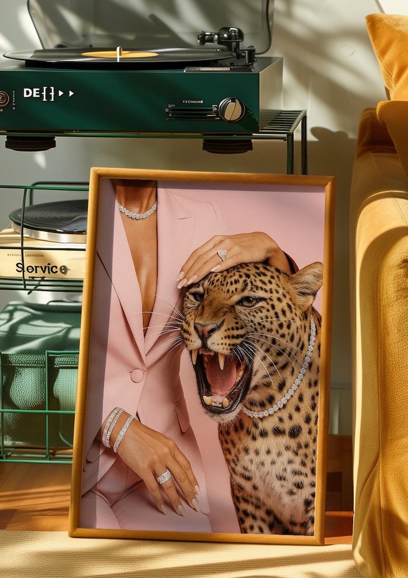 May include: Framed artwork featuring a woman in a pink suit with diamond jewelry, a roaring leopard, and a hand on the leopard's head. A green record player is in the background.