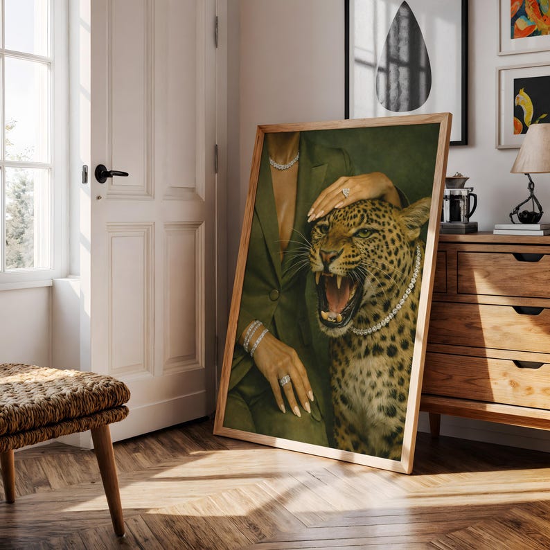 May include: A framed art print featuring a woman in a green suit with a leopard. The leopard is wearing a pearl necklace and has its mouth open. The woman is wearing jewelry, including a bracelet, ring, and necklace. The artwork is in a wooden frame.