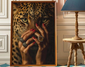 Könnte beinhalten: Gerahmter Kunstdruck mit einem Leoparden, teilweise verdeckt von Händen mit rotem Nagellack und verzierten Ringen. Das Kunstwerk befindet sich in einem goldenen Rahmen, der einen auffälligen Kontrast zum gefleckten Fell des Leoparden bildet.