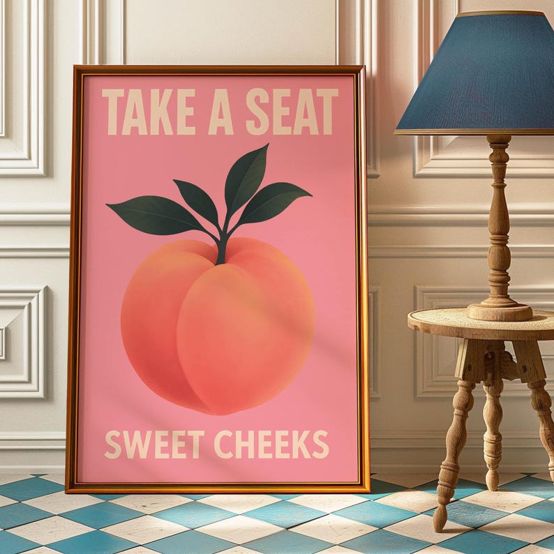 Puede incluir: Impresi&oacute;n art&iacute;stica enmarcada con una ilustraci&oacute;n de melocot&oacute;n sobre fondo rosa. El texto "TAKE A SEAT" y "SWEET CHEEKS" en beige claro. El marco es dorado. Una pieza decorativa para el hogar.