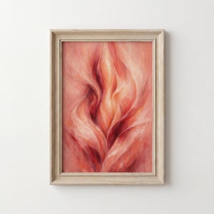 May include: Framed abstract art print. The artwork features a close-up of a floral design in shades of red, orange, and pink. The image has a soft, flowing appearance, with a light-coloured wooden frame.