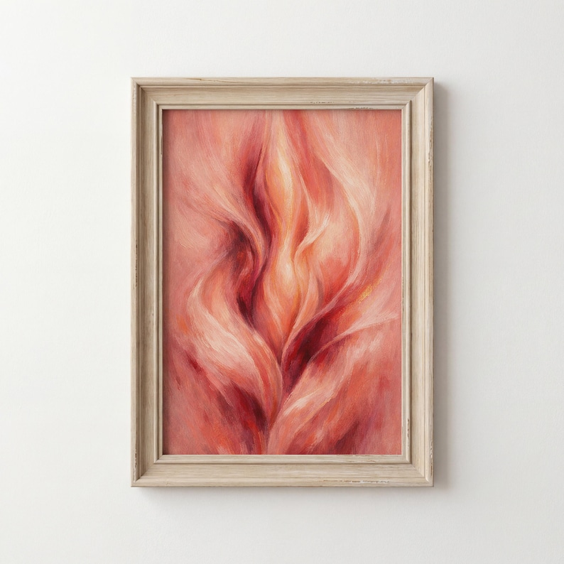 May include: Framed abstract art print. The artwork features a close-up of a floral design in shades of red, orange, and pink. The image has a soft, flowing appearance, with a light-coloured wooden frame.