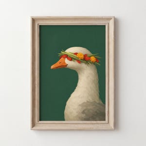 May include: Framed art print featuring a white goose with an orange beak and a floral crown. The goose is set against a dark green background. The frame is a light beige color.