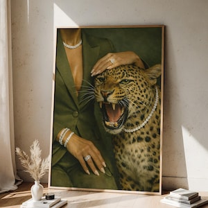 May include: A framed print featuring a woman in a green blazer with diamond jewelry, petting a roaring leopard wearing a diamond necklace. The artwork has a vintage aesthetic with a neutral background.
