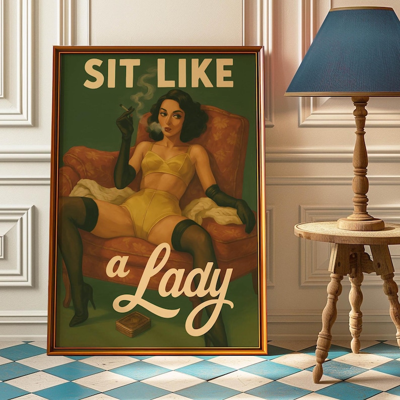 May include: Framed vintage-style print with the text "SIT LIKE a Lady." The artwork depicts a woman in yellow lingerie, black gloves, and stockings, seated in a red armchair, smoking a cigarette. The print has a gold frame.