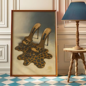 Op de afbeelding: Een ingelijst kunstwerk toont een paar sandalen met hoge hakken met een luipaardprint. De schoenen lijken te smelten in een plas van hetzelfde patroon. Het kunstwerk staat in een kamer met een blauw-witte geblokte vloer.