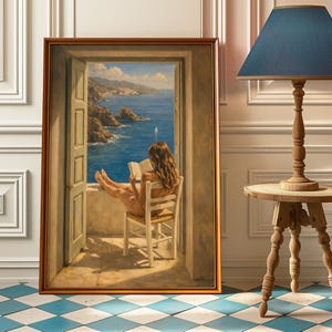 Puede incluir: Pintura enmarcada que representa a una mujer leyendo un libro, sentada en una silla, con vista a la costa a través de una puerta abierta. La pintura está en un marco dorado. Una lámpara con pantalla azul está cerca.