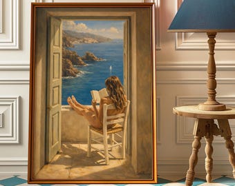 May include: A framed painting depicts a woman reading a book while seated on a chair, with a scenic view of the ocean and coastline visible through an open doorway. The painting is in a gold frame, and a lamp with a blue shade sits nearby.