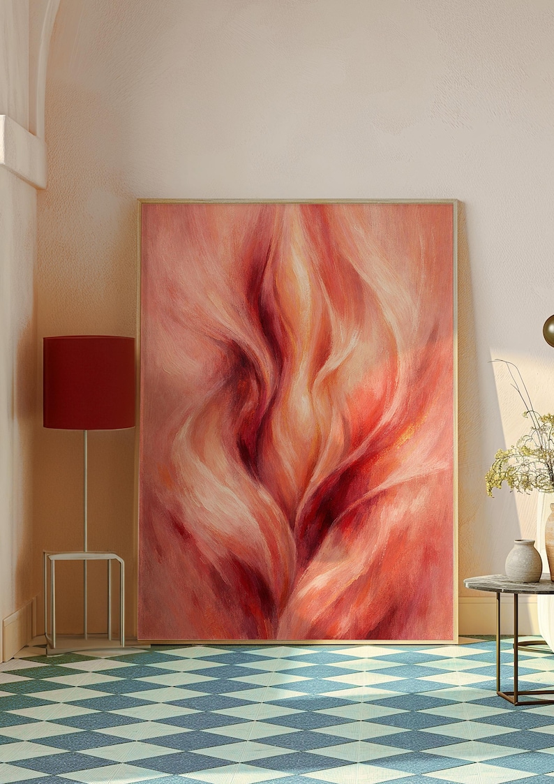 May include: Large framed abstract painting with a wooden frame. The artwork features flowing brushstrokes in shades of red, pink, and cream. The painting is displayed in a room with a red lamp and a patterned floor.