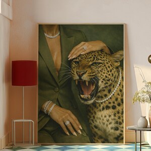 May include: A framed artwork featuring a leopard with an open mouth, wearing a diamond necklace. A person in a green blazer and diamond jewelry is touching the leopard. The artwork is displayed in a room with a red lamp and a blue and white checkered floor.