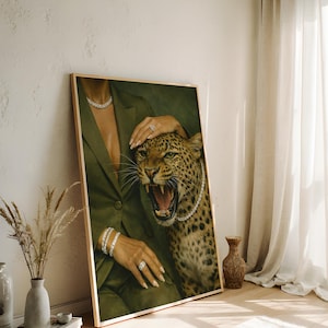 May include: A framed art print featuring a woman in a green blazer with a leopard. The woman is wearing diamond jewelry, including a necklace, bracelets, and rings. The leopard has a diamond necklace and is roaring.