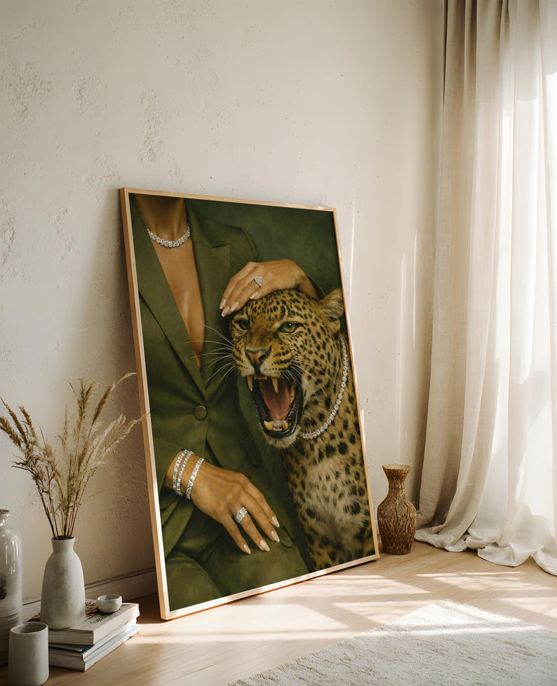 May include: A framed art print featuring a woman in a green blazer with a leopard. The woman is wearing diamond jewelry, including a necklace, bracelets, and rings. The leopard has a diamond necklace and is roaring.