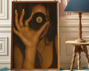 May include: Framed art print featuring a close-up of a person holding an eight ball in front of their face. The person is wearing rings. The print has a gold frame and is displayed against a white wall. A blue and white checkered floor is in the foreground.