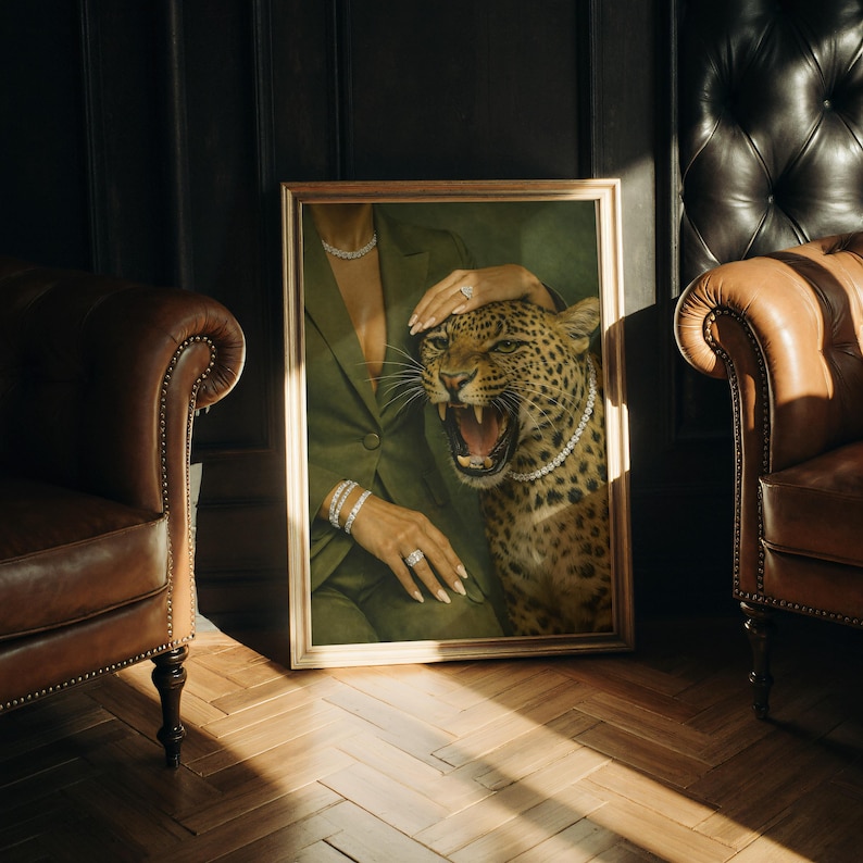 May include: A framed artwork featuring a woman in a green blazer with a leopard. The leopard is wearing a pearl necklace. The woman is wearing jewelry, including a bracelet and ring. The artwork is in a gold frame.