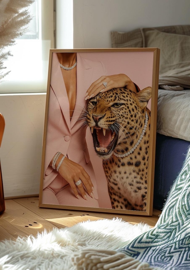 May include: Framed art print featuring a pink suit, a roaring leopard, and diamond jewelry. The artwork includes a diamond necklace, bracelets, and rings. The leopard has a diamond necklace. The frame is made of wood.