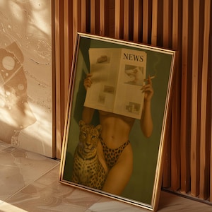 May include: Framed art print featuring a woman holding a newspaper with the word "NEWS" visible. She is wearing leopard print underwear and has a leopard next to her. The artwork has a gold frame and is leaning against a wooden wall.
