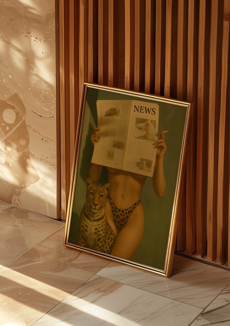 May include: Framed art print featuring a woman holding a newspaper with the word "NEWS" visible. She is wearing leopard print underwear and has a leopard next to her. The artwork has a gold frame and is leaning against a wooden wall.