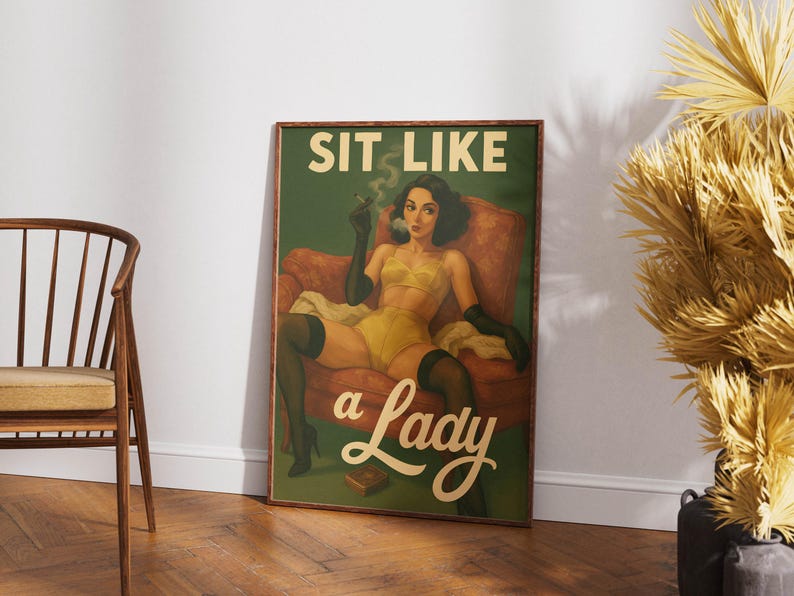 May include: A framed vintage-style poster with the text "SIT LIKE a Lady." The artwork depicts a woman in yellow lingerie, black gloves, and stockings, seated in a red armchair, smoking a cigarette. The background is green.