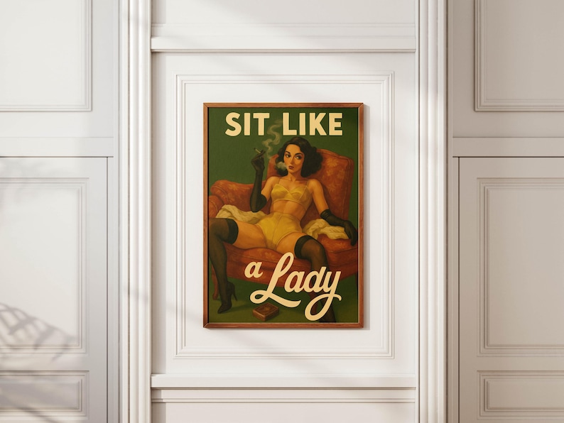 May include: A framed vintage-style print featuring a woman in yellow lingerie, black gloves, and stockings, seated in a red armchair. The print has the text "SIT LIKE a Lady" in a retro font against a green background.