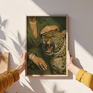 May include: A framed art print featuring a woman in a green blazer and a snarling leopard. The woman wears diamond jewelry, including a necklace, bracelets, and a ring. The leopard also wears a diamond necklace. The artwork has a vintage aesthetic.
