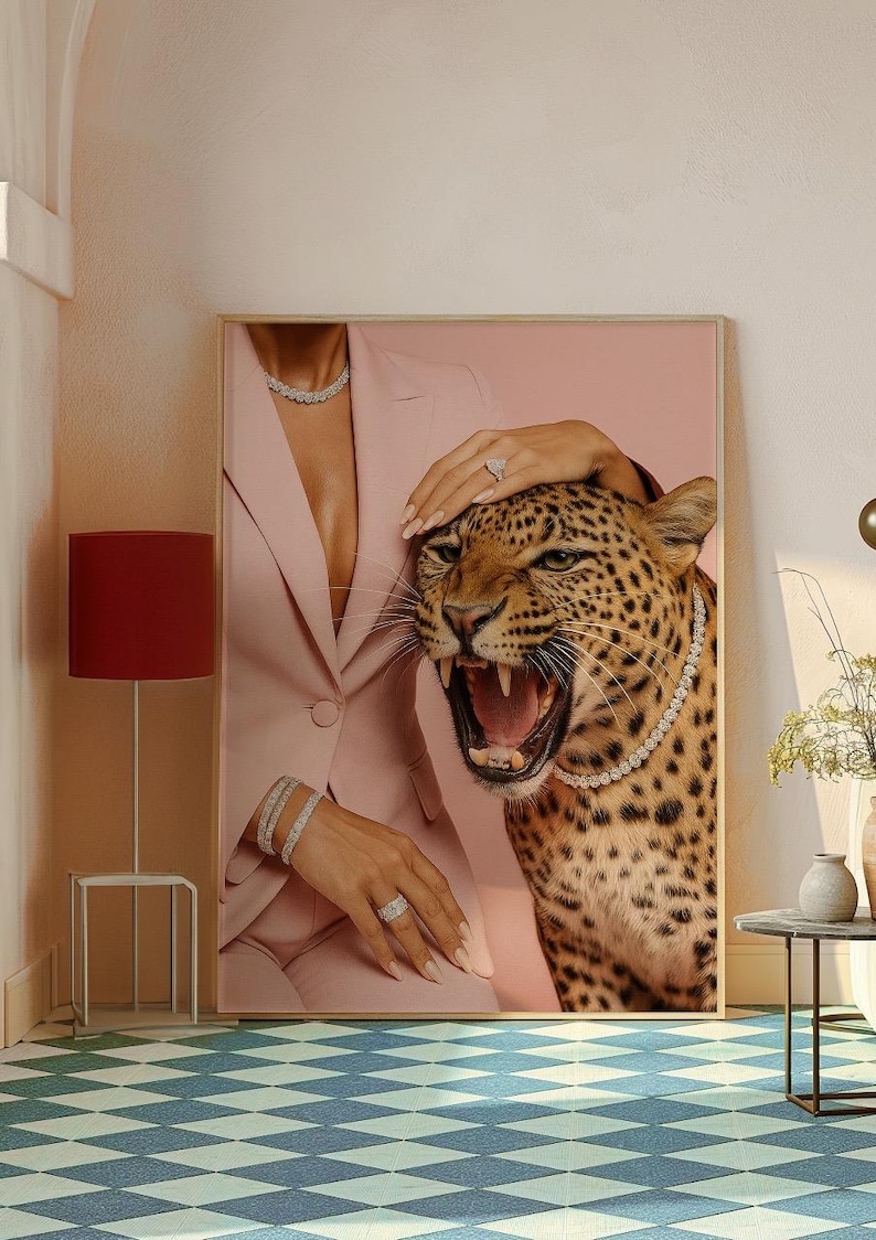 May include: A framed artwork featuring a roaring leopard wearing a diamond necklace, with a woman in a pink suit and diamond jewelry. The leopard's fur is spotted, and the woman's hand rests on its head. The background is a soft pink.