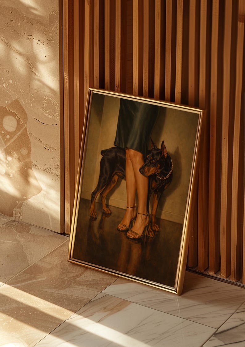 May include: Framed artwork featuring a Doberman Pinscher standing near a person's legs. The person wears a dark green skirt and gold-colored high heels. The dog has a gold chain collar. The artwork is in a gold frame and leans against a wooden wall.