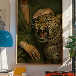 May include: A framed art print featuring a roaring leopard adorned with a diamond necklace. The image includes a person wearing a green blazer and diamond jewelry. The artwork is displayed in a room with a record player and a blue lamp.