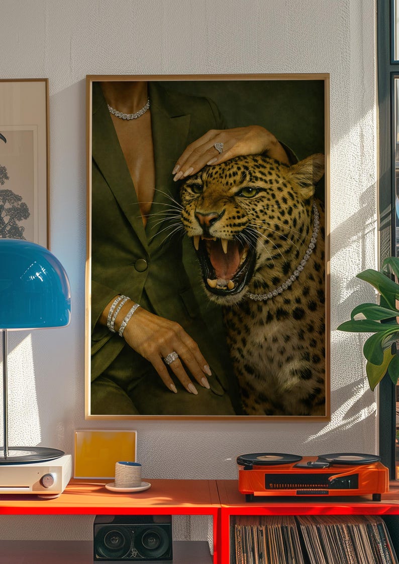 May include: A framed art print featuring a roaring leopard adorned with a diamond necklace. The image includes a person wearing a green blazer and diamond jewelry. The artwork is displayed in a room with a record player and a blue lamp.